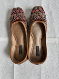 Pair of embroidered slippers on a textured red surface