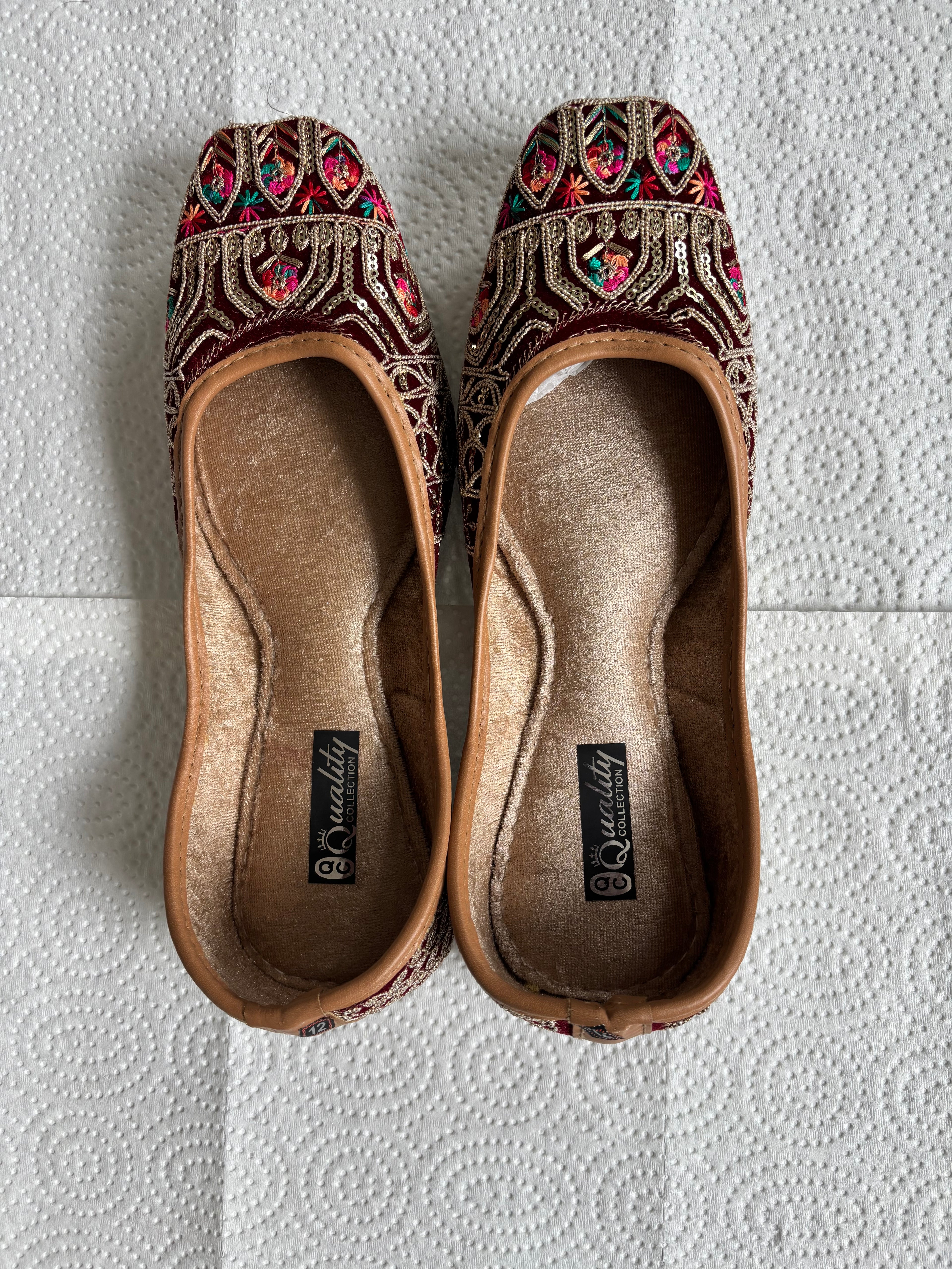 Pair of embroidered slippers on a textured red surface