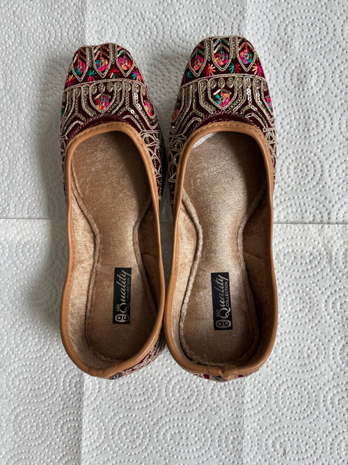 Pair of embroidered slippers on a textured red surface